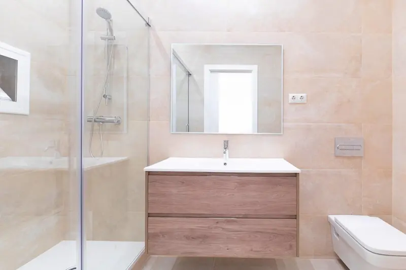 Baño con mueble de madera y revestimiento en tono rosado