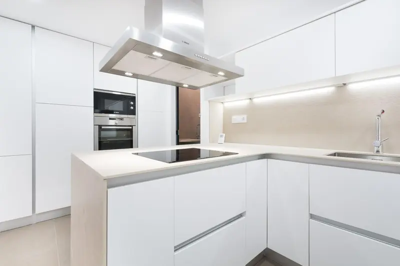 Cocina blanca con península y campana de acero