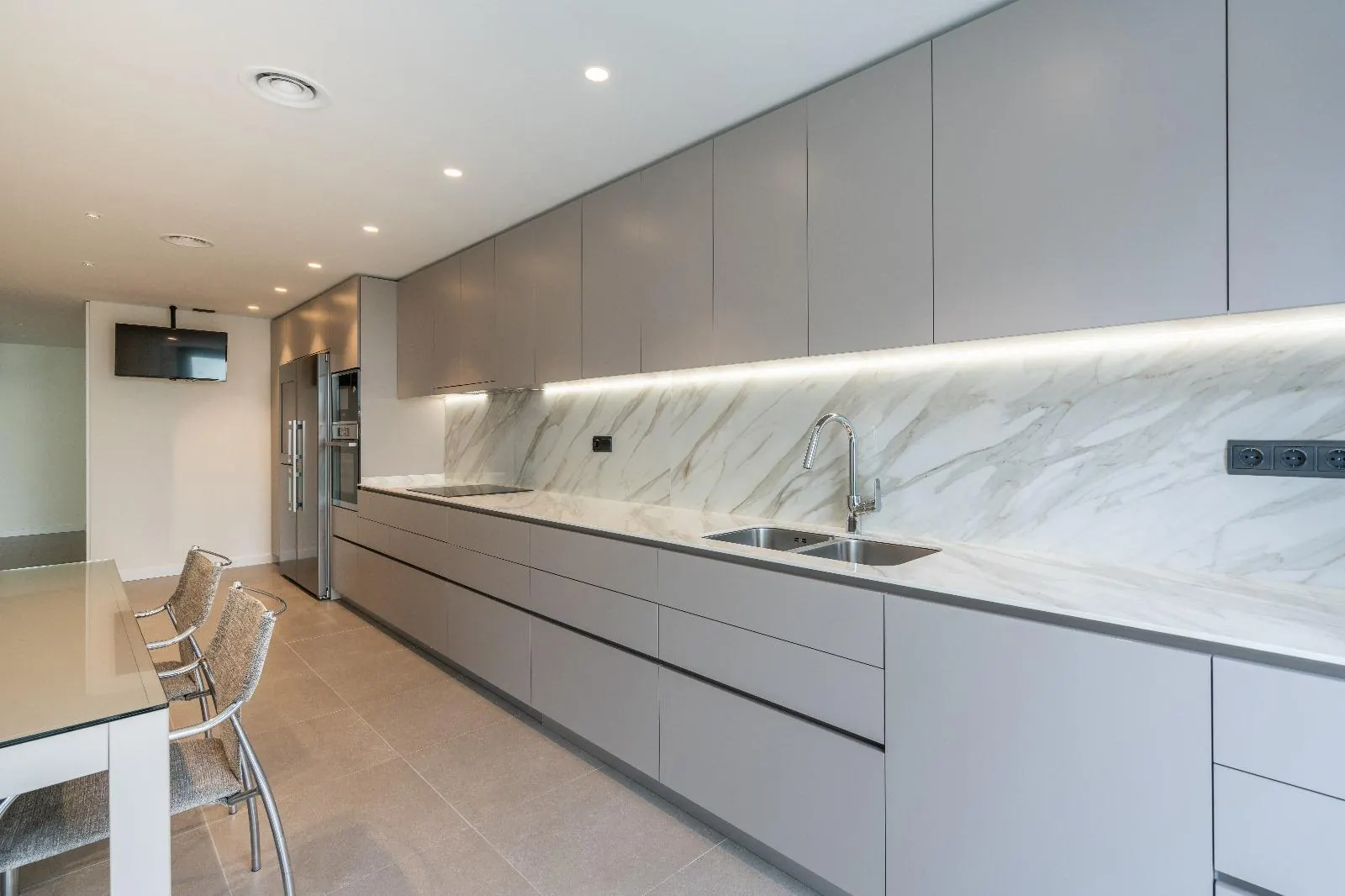 Cocina lineal gris con frente de porcelánico efecto mármol